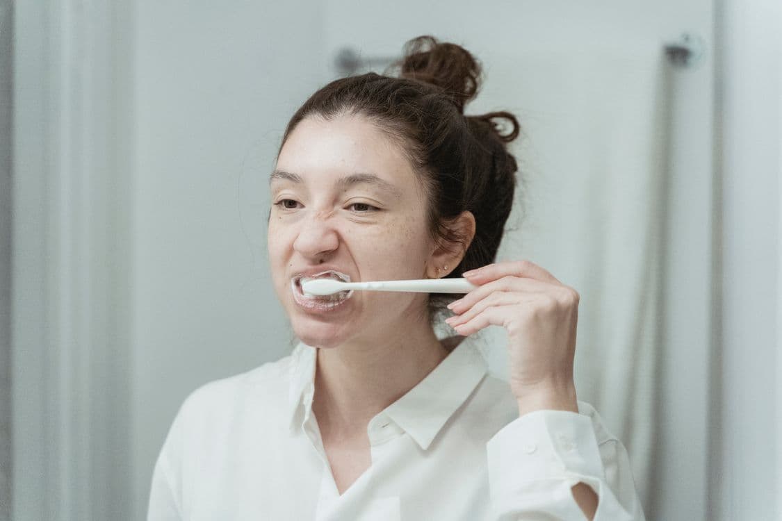 Woman brushing her teeth as part of her morning dental routine