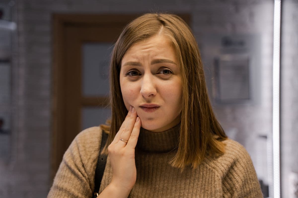Woman holding her jaw and cheek in pain from a tooth abscess