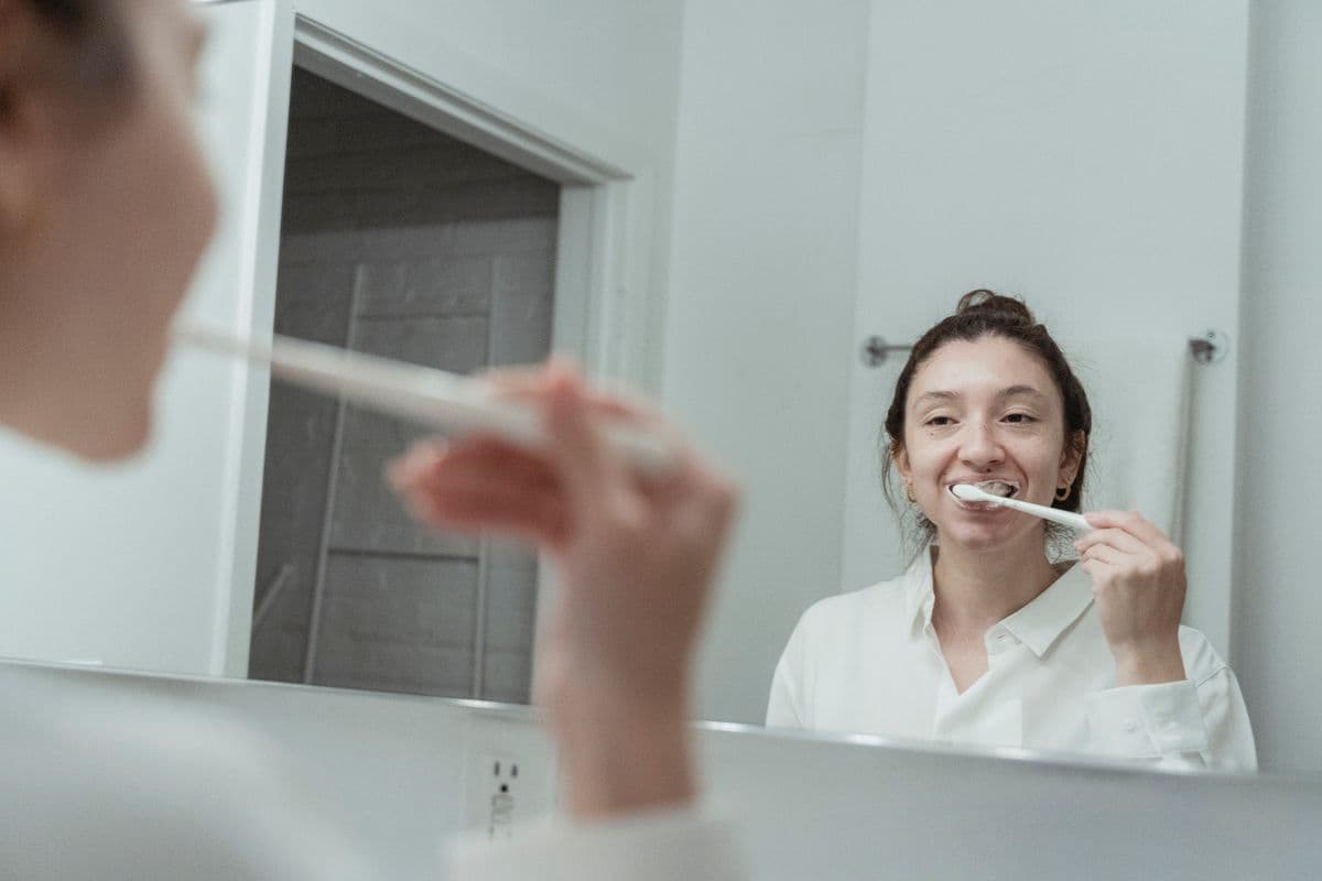 Person brushing their teeth at a bathroom mirror