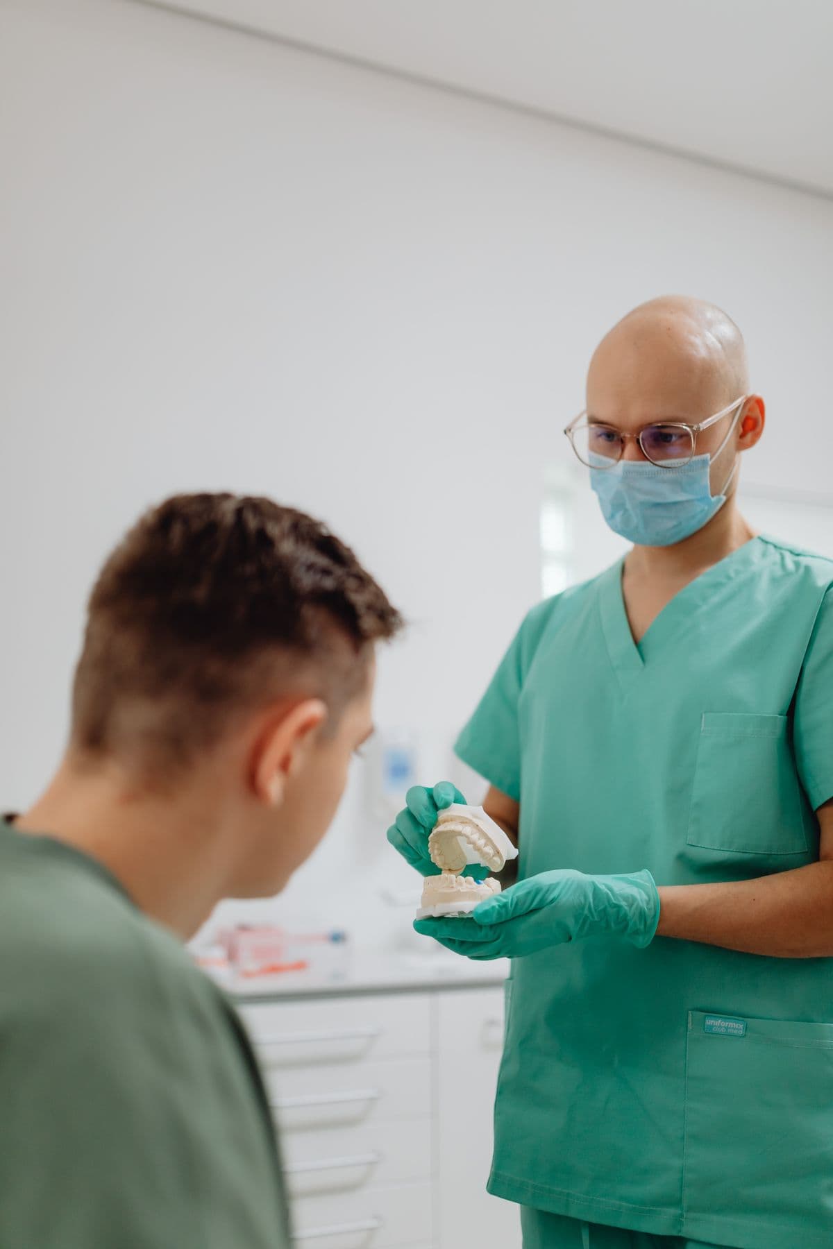 A dentist discussing a dental model with a patient during a restorative dentistry consultation