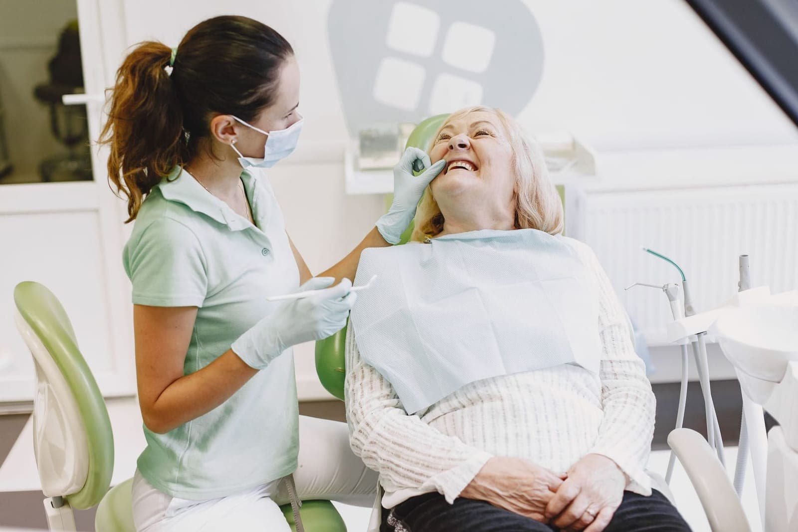 A dental professional examining a smiling patient's teeth during a routine check-up