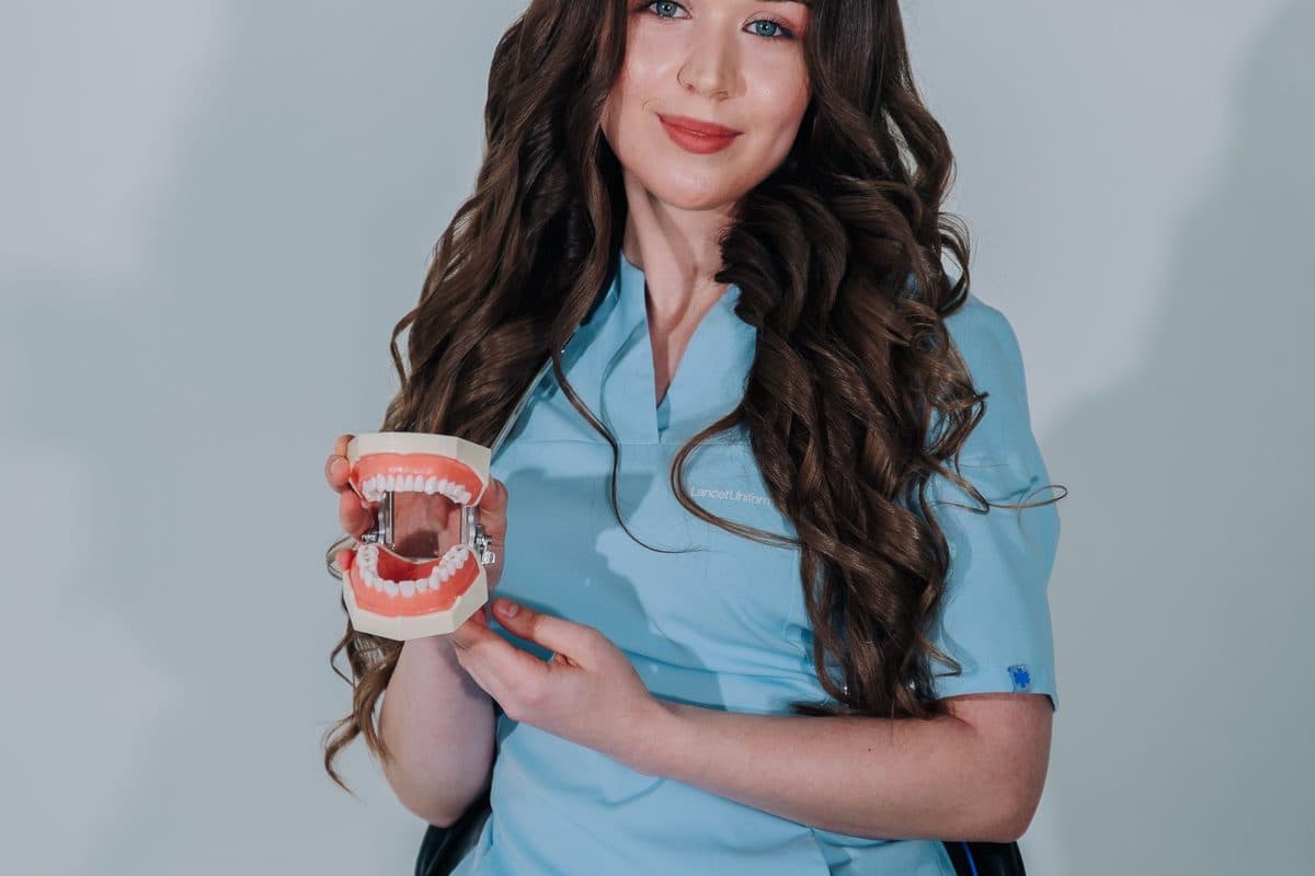 A friendly dental professional holding a model of a set of teeth used for patient education