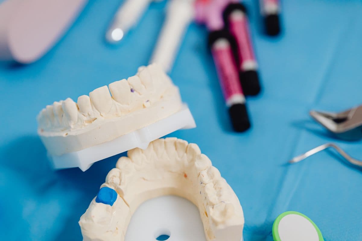 Dental jaw cast models and instruments laid out on a blue surface, representing the crown-making process