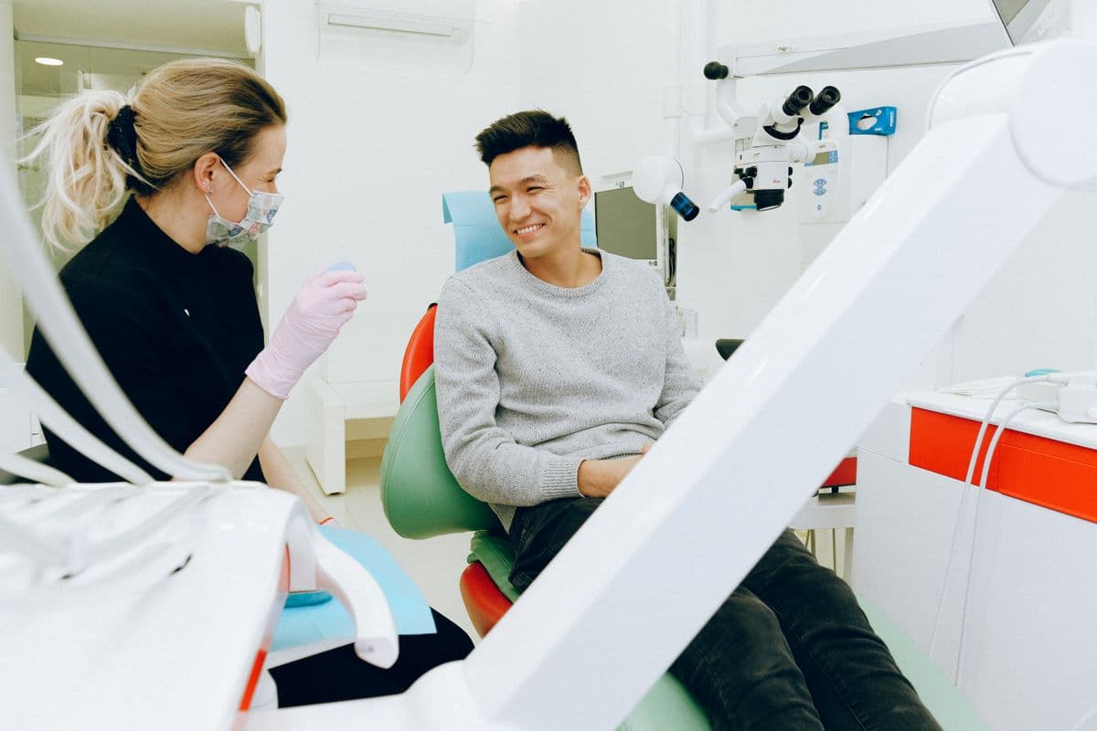 Patient relaxing in a dental chair having a friendly conversation with a dentist