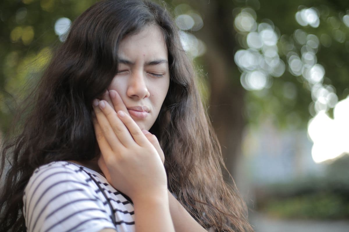Young person holding their jaw in discomfort from wisdom tooth pain